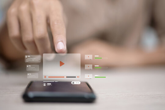 Finger tapping smartphone screen to play online video interface, digital media streaming concept