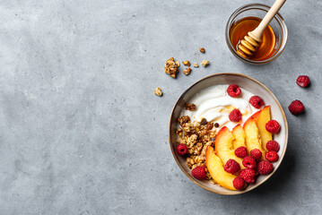 Granola bowl with yogurt, peach, raspberry and honey