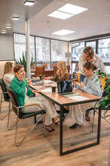 Obraz premium Businesswomen Meeting Laptops: Team collaborates at office table for strategy session, daytime work talk.