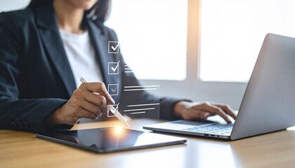 Woman completes digital checklist on tablet while using laptop in bright modern office