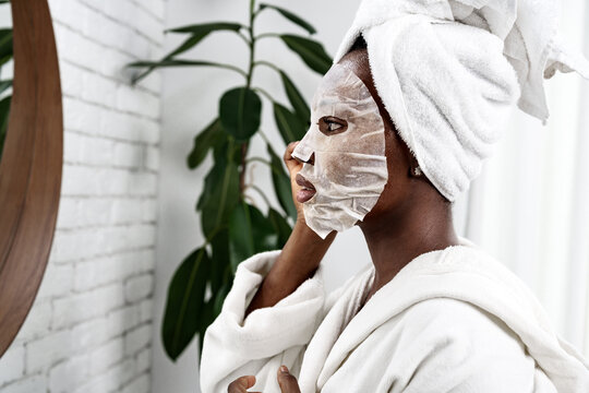 Woman applying a face mask while looking in the mirror at home spa setting during morning routine - Powered by Adobe
