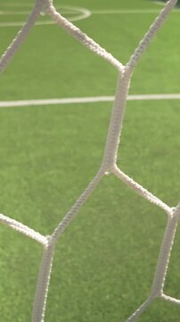 Slide shot behind empty football goal keepers net on 5-a-side pitch VERTICAL