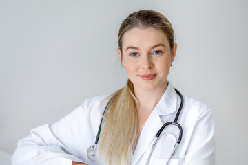 Smiling female doctor with stethoscope in a white medical coat indoors