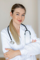 Confident female doctor in white coat with a stethoscope smiling at camera