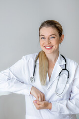 Smiling female doctor with stethoscope in a white medical coat indoors