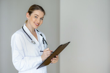 Smiling medical professional writing notes on a clipboard in clean environment