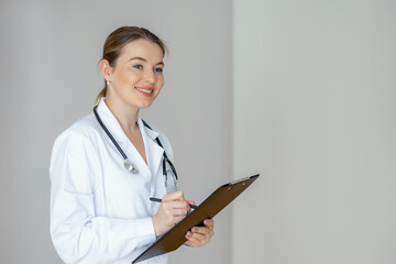 Smiling female doctor writing on a clipboard in a medical environment