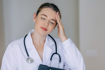Tired Female Doctor With Stethoscope Touching Her Head in Thought