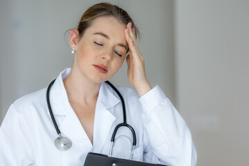 Stressed female doctor with hand on her head wearing a white coat