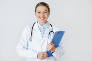Smiling female doctor holding a clipboard in a bright medical setting