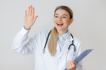 Smiling female doctor welcoming patients with clipboard and stethoscope in office