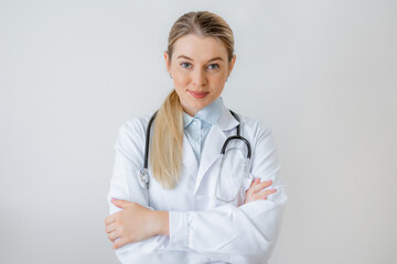 Portrait of a confident doctor with stethoscope standing against a plain background