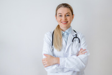 Smiling female doctor in white coat with stethoscope standing confidently