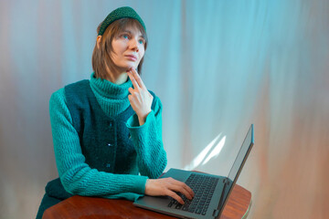 A beautiful young woman is working or playing or shopping on a laptop in a stylish modern dress and a hair band in the shape of the Russian national kokoshnik headdress