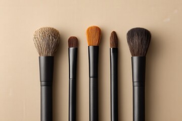 Flat lay of makeup brushes with matte black handles aligned vertically on subtle gradient background