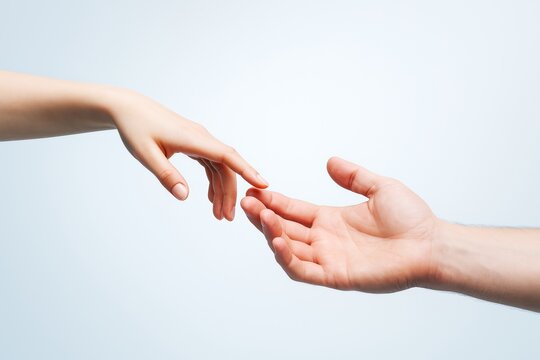 Two human hands reaching toward each other with fingers almost touching on a soft light background, symbolizing connection and trust.