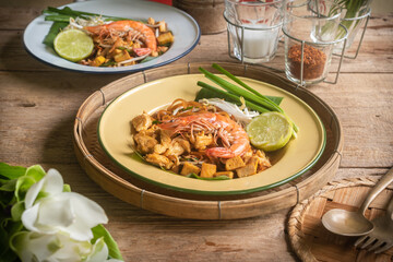 Pad Thai Pad Thai with rice vermicelli and shrimp with ingredients placed on the table.