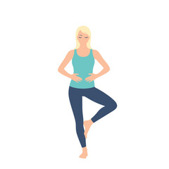 Fototapeta premium A blonde woman in blue sportswear is practicing yoga, standing in the tree pose with hands clasped near her stomach, isolated on a white background.