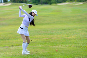 Asian woman happy and fun while playing golf on the golf course. Golfer hitting golf shot with...