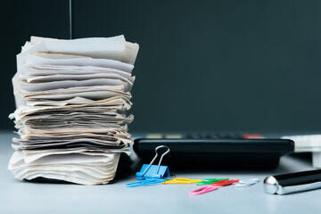 Large stack of paper receipts on a finance desk with calculator, pen, and colorful paper clips, symbolizing financial records, bookkeeping, or tax document organization