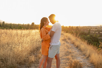 Couple Embracing at Sunset in a Scenic Landscape With Golden Grass and Warm Tones