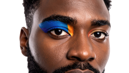 Close-up of a man's face featuring bold blue and orange eye makeup on his right eyelid.