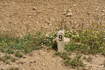 Borne kilométrique numéro 9 au bord d'un chemin à la campagne.