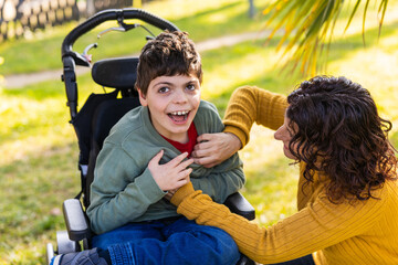 Mother comforting her son with disability sitting in a wheelchair in a park