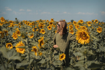 A girl in a pink skirt and a white T-shirt walks through a field of blooming yellow sunflowers. A woman dances, rejoices, smiles, enjoys life, warmth, summer, the sun. High quality FullHD footage