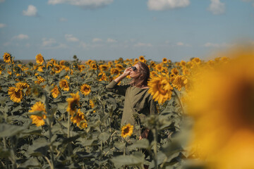 A girl in a pink skirt and a white T-shirt walks through a field of blooming yellow sunflowers. A woman dances, rejoices, smiles, enjoys life, warmth, summer, the sun. High quality FullHD footage
