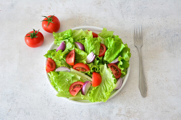 Fresh Salad with Tomatoes and Red Onion on a White Plate with a fork