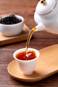 Tea leaves and tea set interior scene, pouring tea from kettle into cup