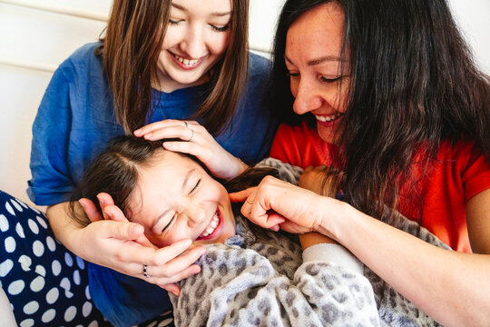 Mother with daughters bonding affectionately at home smiling