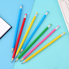 Pencils of various colors placed on a blue paper, children's learning stationery