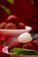 Lychees peeled to reveal the flesh, close-up shot on red studio background