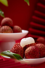 Lychees peeled to reveal the flesh, close-up shot on red studio background