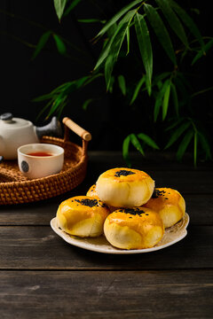 Egg yolk pastry in a Chinese style table setting, dark photography background