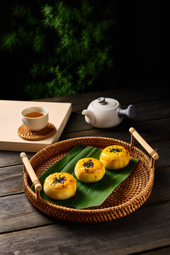 Egg yolk pastry in a Chinese style table setting, dark photography background