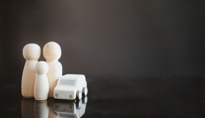 A wooden peg doll family are standing near a wooden car. The concept of buying and selling or car for rent. Reserve money for future use of life partner. Success family