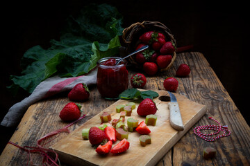 Strawberry rhubarb jam and fresh fruit on rustic wood table