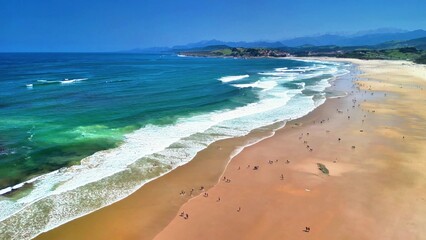 Experience the beauty of a sunny beach, with waves crashing, surfers riding, and people enjoying the warm sand