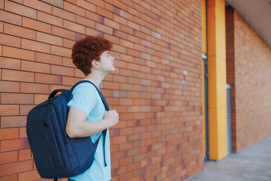Redhead Teen Boy Standing Thoughtfully Near a Modern School Wall