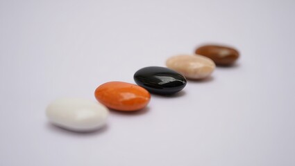 Colorful array of candy coated chocolate lentils in a line against a white background for fun treats