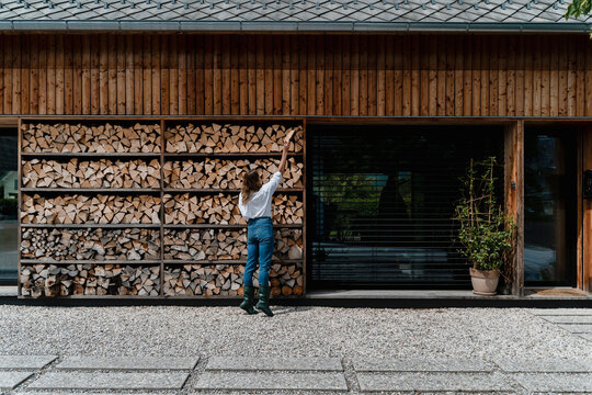 Woman collecting firewood in modern backyard practicing sustainable living
