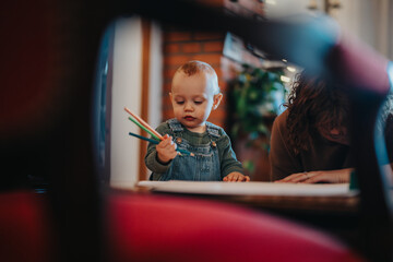 Depicts a child holding crayons with a parent engaged in a creative activity, conveying a sense of...