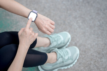Obraz premium Woman is using a smartwatch with a blank screen while sitting on the side of the road