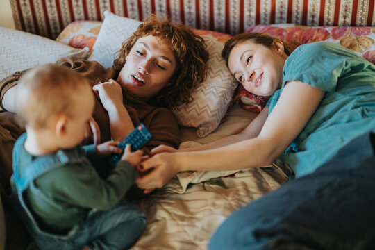 A serene moment of a family enjoying quality time together, fostering connection and love while lying on a comfortable bed in a cozy setting. - Powered by Adobe