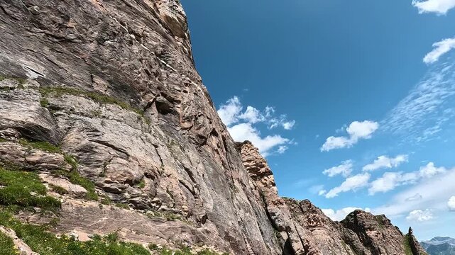 Jagged rocky ridge and vast alpine valley beneath a bright blue sky in the Alpe Devero region, Italian Alps.