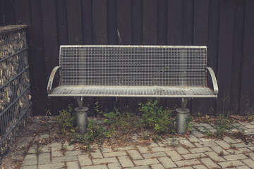 Rustic metal bench surrounded by overgrown greenery in an urban setting invites moments of...