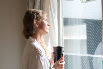 young woman enjoying drinking tea in the hotel room in the morning